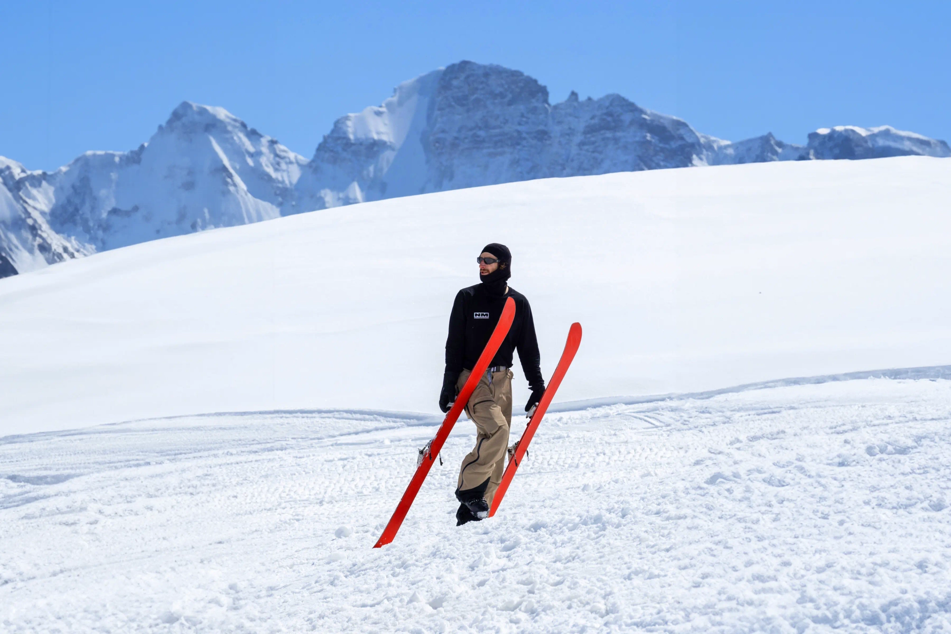 Alex Hackel Walking in Snow Holding Skis